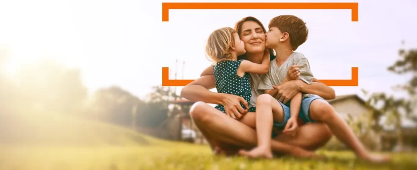 Mother and two children sitting together on a sunny lawn